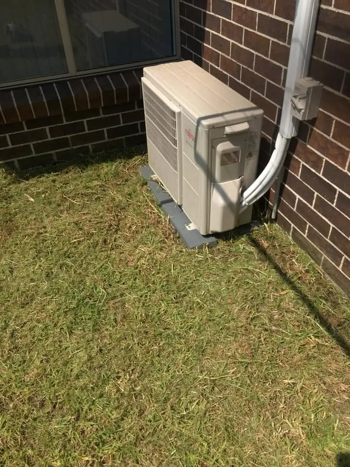 Neatly mowed lawn around the same AC unit after professional maintenance